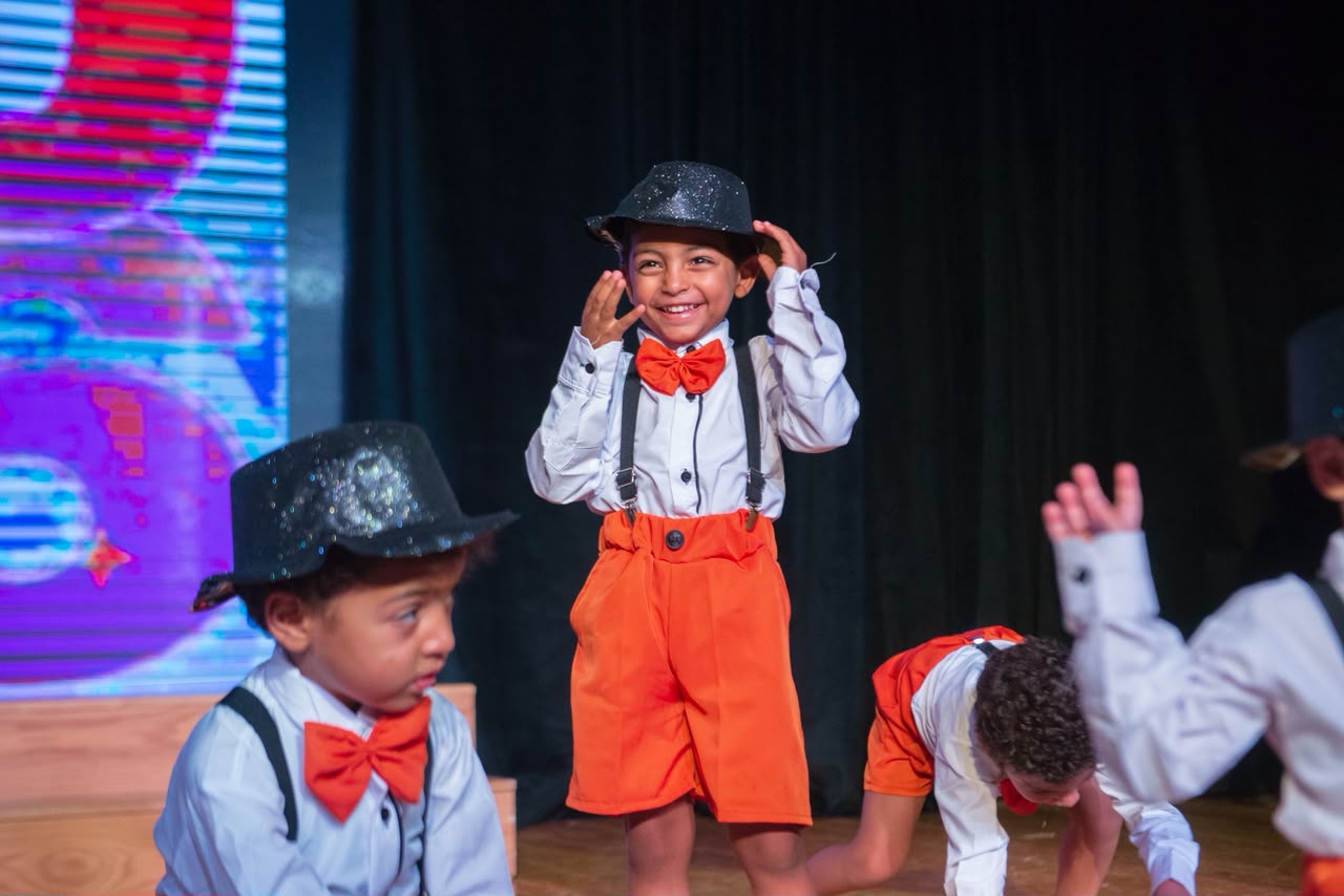 Smiling Andy Pandy graduate in bowtie and hat dancing on stage