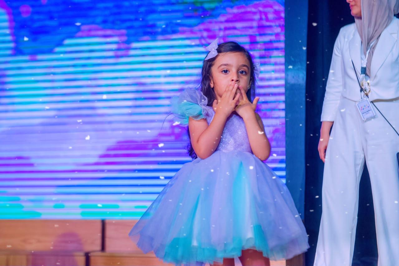 Andy Pandy graduate in a sparkling blue princess dress performing on stage